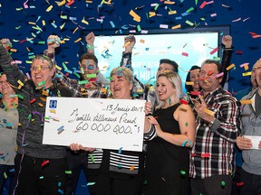 Carl Villeneuve, third from left, and his wife Marie-Josee Picard, fifth from left, of Saguenay Que., hold the $60-million cheque they won playing Lotto Max, during a news conference at the Loto Quebec office, Monday, February 13, 2017 in Quebec City. The Villeneuve-Picard couple decided to split their earnings with 11 family members. THE CANADIAN PRESS/Jacques Boissinot