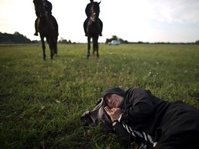 An elderly Afghan migrant rests on the ground of a field while she and others are being detained by Hungarian police on horses for sneaking through Hungary's border fence with Serbia, in Asotthalom, Hungary, on Sept. 16, 2015. (Muhammed Muheisen/AP Photo/Files)