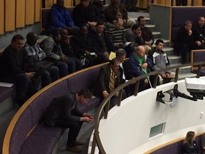 Amid a crowd of people representing London's traditional taxi industry, the lone Uber official present, Chris Schafer, (front row) checks his smartphone before a crucial council debate on taxi bylaws at city hall Tuesday. (PATRICK MALONEY, The London Free Press)