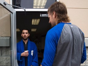 Toronto Blue Jays starting pitcher Marco Estrada, left, waits in his robe next to Matt Dermody as pitchers and catchers reported for their medicals in Dunedin, Fla., on Feb. 14, 2017. (THE CANADIAN PRESS/Nathan Denette)