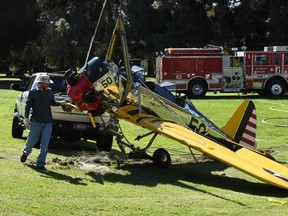 This file photo taken on March 6, 2015 shows firefighters and an aviation official remove the 1942 Ryan Aeronautical ST3KR plane that crashed onto a golf course and was piloted by US actor Harrison Ford in Venice, California. Hollywood star Harrison Ford was involved in a near-miss at a California airport on Febuary 14, 2017 as he was piloting his private plane, officials and US media said. Ford, a seasoned pilot and vintage plane collector, was approaching John Wayne Airport in Orange County, NBC reported, when he headed towards a taxiway rather than the runway, passing over a Boeing 737 with 110 passengers and six crew. (MARK RALSTON/AFP/Getty Images)