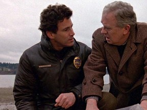 Canadian actor Michael Ontkean (as Sheriff Harry S. Truman) (left) and American actor Warren Frost (as Dr. Will Hayward) talk as they examine a plastic-wrapped body on a rocky beach in a scene from the pilot episode of the television series 'Twin Peaks,' originally broadcast on April 8, 1990. (CBS Photo Archive/Getty Images)