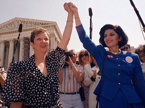 In this April 26, 1989 file photo, Norma McCorvey, Jane Roe in the 1973 court case, left, and her attorney Gloria Allred hold hands as they leave the Supreme Court building in Washington after sitting in while the court listened to arguments in a Missouri abortion case. (AP Photo/J. Scott Applewhite, File)