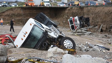 Officials look over the scene, Saturday, Feb. 18, 2017,  where  a tractor trailer fell Friday from southbound Interstate 15 where part of the freeway collapsed due to heavy rain in the Cajon Pass, Calif., Saturday, Feb. 18, 2017   A huge Pacific storm that parked itself over Southern California and unloaded, ravaging roads, opening sinkholes  eased off Saturday but it was only a temporary reprieve as new storms took aim farther north. (David Pardo/The Daily Press via AP)