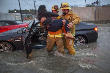 A firefighter carries a woman from her car after it was caught in street flooding as a powerful storm moves across Southern California on Feb. 17, 2017 in Sun Valley, Calif.  (David McNew/Getty Images)