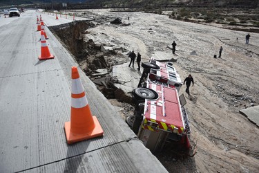 Officials look over the scene where a San Bernardino County Fire Department fire engine fell Friday from southbound Interstate 15 where part of the freeway collapsed due to heavy rain in the Cajon Pass, Calif., Saturday, Feb. 18, 2017. (David Pardo/The Daily Press via AP)