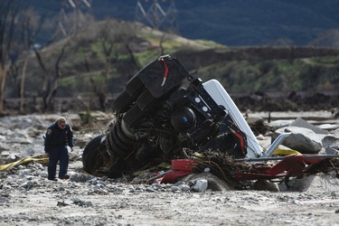 An official looks over the scene, Saturday, Feb. 18, 2017,  where a tractor trailer and a San Bernardino County Fire Department fire engine fell Friday from southbound Interstate 15 where part of the freeway collapsed due to heavy rain in the Cajon Pass, Calif.  (David Pardo/The Daily Press via AP)