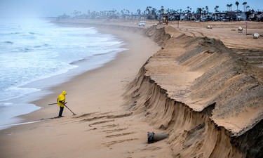 Stan Ross of Newport Beach digs up some sand near the Balboa Pier in Newport Beach, Calif., early Saturday, Feb. 18, 2017, as he looks for coins and jewelry following Friday's storm that eroded the beach, brought high winds, and heavy rain which flooded many areas in Southern California. (Mark Rightmire/The Orange County Register via AP)