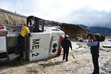 Officials look over the scene, Saturday, Feb. 18, 2017,  where  a San Bernardino County Fire Department fire engine fell Friday from southbound Interstate 15 where part of the freeway collapsed due to heavy rain in the Cajon Pass, Calif.  (David Pardo/The Daily Press via AP)