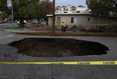 A large 20-foot-deep (6-meter) sinkhole that swallowed two vehicles in North Laurel Canyon Blvd, in Los Angeles, is cordoned-off on Feb. 18, 2017, after a powerful storm hit southern California. (MARK RALSTON/AFP/Getty Images)