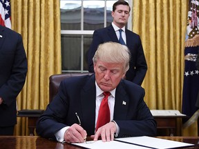 U.S. President Donald Trump signs an executive order as Vice-President Mike Pence looks on at the White House in Washington, D.C. on Jan. 20, 2017. (JIM WATSON/AFP/Getty Images)