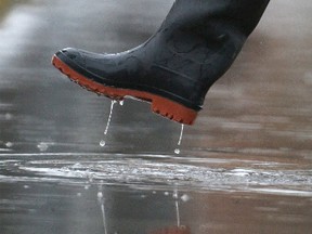 A person wearing rubber boots walks through a puddle, in Winnipeg. Light rain is not normal in the end of February, in Winnipeg. Monday, February 20, 2017. Chris Procaylo/Winnipeg Sun/Postmedia Network