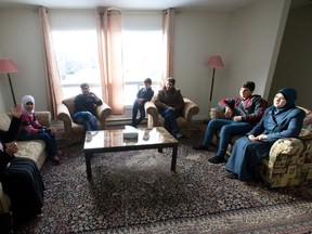 Cross Cultural Learner Centre housing coordinator Perihan El Shamy, left, speaks with members of the Ghozlan family - Ayah, Feras, Mohammad, Maan Ali, Nour Aldeen and Rajaa Abdulhadi - to see how the Syrian nationals are settling into their Upper Queens Avenue home in London, Ont. on Tuesday January 19, 2016. (Free Press file photo)