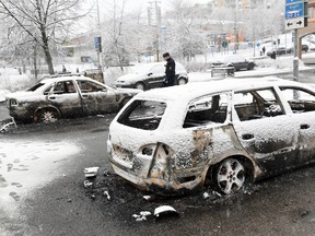 In this picture taken on Monday, Feb. 20, 2017,a policeman investigates a burned out car in the suburb of Rinkeby outside Stockholm. Police in Sweden said Tuesday they were investigating riots that broke out overnight in a predominantly immigrant Stockholm suburb after officers arrested a suspect on drug charges. Spokesman Lars Bystrom said unidentified people, including some wearing masks, threw rocks at police, set cars on fire and looted shops in Rinkeby, north of Stockholm. (Christine Olsson/TT News Agency via AP)