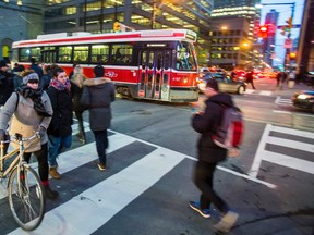 Pedestrians make their way across Bay St. at King St. W. in downtown Toronto, late last month. State Farm Canada, the insurance company, says 40% of Canadians admitted to wexting and 25% usually walk while wearing ear buds. (ERNEST DOROSZUK/TORONTO SUN)