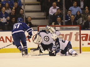 Maple Leafs defenceman Jake Gardiner scores the game-winner in overtime past Jets goalie Connor Hellebuyck during last night’s game in Toronto. (JACK BOLAND/Postmedia Network)