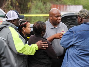 LeCarious Oliver of the Mississippi Bureau of Investigation speaks with family members at a scene where authorities are investigating the shooting deaths of four members of a family in Toomsuba, Miss., Tuesday, Feb. 21, 2017. (Paula Merritt /The Meridian Star via AP)