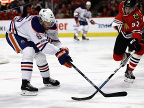 Adam Larsson #6 of the Edmonton Oilers reaches for the puck as Trevor van Riemsdyk #57 of the Chicago Blackhawks pokes it away at the United Center on February 18, 2017 in Chicago, Illinois.