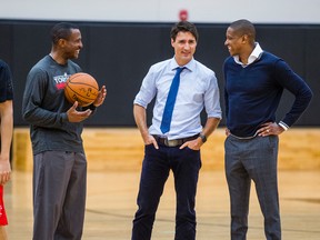 Canadian Prime Minister Justin Trudeau chats with Toronto Raptors head coach Dwane Casey and president Masai Ujiri while they watch visiting students of La Loche Community School in Saskatchewan on Jan. 13, 2017. (Ernest Doroszuk/Toronto Sun/Postmedia Network)