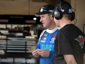 D.J. Kennington, left, watches crew members work on his car during practice for Sunday's Daytona 500 at Daytona International Speedway in Daytona Beach, Fla., Friday, Feb. 24, 2017. (AP Photo/Phelan M. Ebenhack)