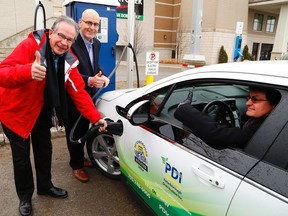 MPP Jeff Leal next to Ontario's Minister of Transportation Steven Del Duca prepare to charge an electric car with as David Whitehouse, director of customer and corporate services/conservation officer with Peterborough Utilities Group behind the wheel at the location of two charging stations for electric cars on Friday February 24, 2017 at Lansdowne Place mall parking lot in Peterborough, Ont.  Clifford Skarstedt/Peterborough Examiner/Postmedia Network