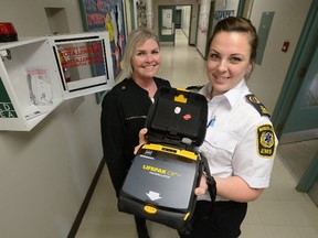 Miranda Bothwell, public education coordinator for Middlesex-London EMS, right, and Mary Ellen cornelius, principal of St Martins Catholic School, show Automatic External Defibrillator in the hall of the school. (MORRIS LAMONT, The London Free Press)