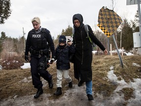 A mother and son are escorted by a Royal Canadian Mounted Police officer after they illegally crossed the U.S.-Canada border into Canada, Feb. 23, 2017 in Hemmingford, Quebec. In the past month, hundreds of people have crossed Quebec land border crossings in attempts to seek asylum and claim refugee status in Canada. (Photo by Drew Angerer/Getty Images)