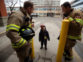(left to right) Edmonton Fire Fighters Troy Farn and Courtney Polson chat with Cedric Way, 6, before climbing onto the roof of Fire Station #2 (10217 - 107 St.) to start their annual Rooftop Campout in support of Muscular Dystrophy Canada, in Edmonton Tuesday Feb. 21, 2017. Cedric has Duchenne muscular dystrophy. Photo by David Bloom