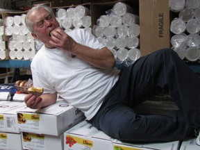Gus Pantazis stretches out on cases of fruit fillings Saturday to enjoy a paczki made in the kitchen of his Global Donuts and Deli on London Road in Sarnia. The shop has been making the Polish pastries in the days leading up to Lent for the last three decades. (Paul Morden/Sarnia Observer)