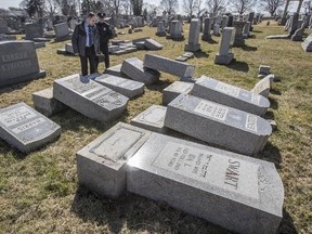 Northeast Philadelphia Police Detective Timothy McIntyre and a Philadelphia police officer look over tombstones that were vandalized at Mount Carmel Cemetery in Philadelphia on Sunday, Feb. 26, 2017. (Michael Bryant/The Philadelphia Inquirer via AP)