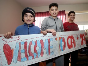 Ibraheim Al Jalam, right, cousin of sick Syrian boy Bilal Al Jalam, holds up a welcome to Canada sign with Syrian-Kingston friends Ouday Al Jalem, middle and Kousay Al Jalem on Monday. (Ian MacAlpine/The Whig-Standard)