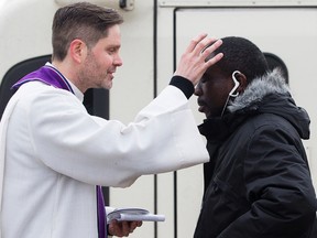 Rev. Jason Anderson offers an LRT commuter The Imposition of Ashes to signify the first day of Lent, at the NAIT LRT station, in Edmonton on Wednesday Feb. 10, 2016.