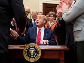 U.S. President Donald Trump shakes hands after signing the Waters of the United States (WOTUS) executive order, Feb. 28, 2017, in the Roosevelt Room in the White House in Washington, which directs the Environmental Protection Agency to withdraw the Waters of the United States (WOTUS) rule, which expands the number of waterways that are federally protected under the Clean Water Act. (AP Photo/Andrew Harnik)