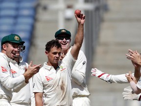 Australia’s Steve O’Keefe, holds up the ball after winning the first test cricket match against India in Pune, India.(AP)