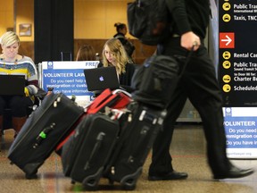 Asti Gallina, center, a volunteer law student from the University of Washington, works at a station near where passengers arrive on international flights at Seattle-Tacoma International Airport Tuesday, Feb. 28, 2017, in Seattle. Gallina was volunteering with the group Airport Lawyer, which also offers a secure website and mobile phone app that alerts volunteer lawyers to ensure travelers make it through customs without trouble. Airport officials and civil rights lawyers around the country are getting ready for President Donald Trump's new travel ban, which is expected to be released as soon as Wednesday. (AP Photo/Ted S. Warren)