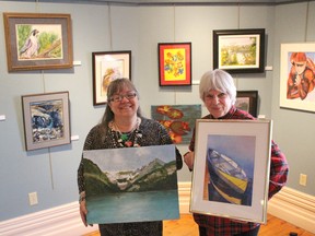 Local artists Patti Cook and Lynne Kenneith Brogden show off two pieces from the exhibit My Canada! at the Lawrence House Centre for the Arts Wednesday. Close to 50 different works from members of the Sarnia Artists' Workshop are featured in the new exhibit set to run for the month of March. Cook is pictured here holding a Jean Poole painting called Lake Louise, Alberta, while Brogden is holding a Liz Rogers painting called Waiting.  Barbara Simpson/Sarnia Observer/Postmedia Network