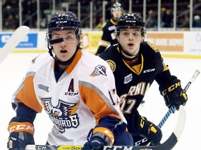 Flint Firebirds' Everett Clark, left, and Sarnia Sting's Drake Rymsha watch the bouncing puck in the first period Wednesday at Progressive Auto Sales Arena. (MARK MALONE/Postmedia Network)