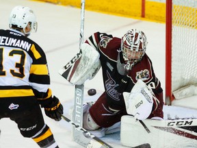 Peterborough Petes' goalie Dylan Wells makes a glove save next to Kingston Frontenacs' Brett Neumann during second-period OHL action at the Memorial Centre in Peterborough. (Clifford Skarstedt/Postmedia Network)