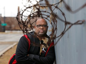 In this Tuesday, Feb. 21, 2017, photo, Pastor Corey Brooks of the New Beginnings Church poses for a portrait on a under maintained security wall that hugs the sprawling Norfolk Southern train yard and his church on Chicago's South Side. When street-gang thieves slipped into a Norfolk Southern rail yard on Chicago's South Side and ripped locks off one train, they likely expected to see merchandise like toys or tennis shoes. What they beheld instead was a gangster’s jackpot: box after box of brand new guns. (AP Photo/Charles Rex Arbogast)