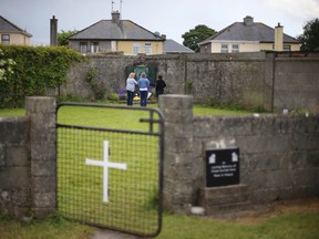 In this June 7, 2014 file photo, members of the public are seen at the site of a mass grave for children who died in the Tuam mother and baby home, in Tuam, Ireland. (Niall Carson/PA via AP, File)