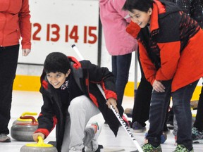 Patricio Linares Salgado (left) and Juan Pablo Gallardo Navarrete, two of 23 students visiting Upper Thames Elementary School and West Perth for two weeks, are all smiles as they give curling a try March 1. ANDY BADER/MITCHELL ADVOCATE