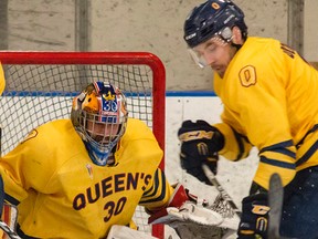 Queen's Gaels goaltender Kevin Bailie keeps his eyes on the puck as defenceman Patrick Downe tries to clear it from the crease area during Ontario University Athletics East Division men's hockey playoff action. (Tim Gordanier/ Whig-Standard file photo)