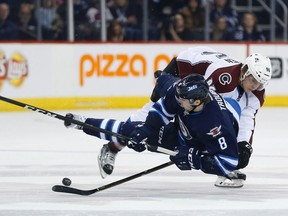 Jets’ Jacob Trouba gets tripped by the Avalanche’s Mikko Rantanen last night. (The Canadian Press)