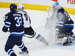 Despite the face-wash, Jets goalie Connor Hellebuyck stops a shot against the Avalanche last night. (The Canadian Press)