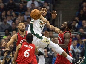 Milwaukee Bucks' Giannis Antetokounmpo passes the ball out after being stopped by Toronto Raptors' Jonas Valanciunas, left, DeMarre Carroll, right, and Cory Joseph, center, during the first half of an NBA basketball game Saturday, March 4, 2017, in Milwaukee. (AP Photo/Tom Lynn)