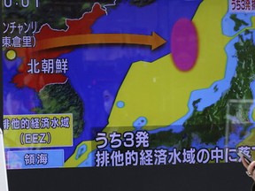 A woman walks past a screen showing a TV news on a missile firing by North Korea with a map of Japan and North Korea in Tokyo, Monday, March 6, 2017. (AP Photo/Koji Sasahara)