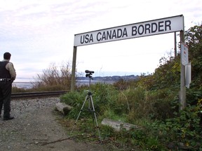 A Canadian Customs and Fisheries officer watches over the U.S.-Canada border between Blaine, Washington and White Rock, British Columbia November 8, 2001 in White Rock, BC. (Photo by Jeff Vinnick/Getty Images)