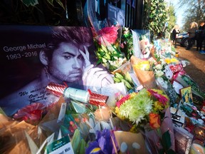 This file photo taken on December 27, 2016 shows people pausing at the pile of flowers, candles and messages left by well-wishers and fans in tribute outside the home of British singer George Michael in north London on December 27, 2016 two days after the singer died.
British pop icon George Michael, who was found dead at his home on Christmas Day 2016, died of natural causes, a coroner announced on March 7, 2017. / AFP PHOTO / NIKLAS HALLE'NNIKLAS HALLE'N/AFP/Getty Images