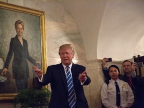 U.S. President Donald Trump walks in a corridor of the White House to greet visitors, while a portrait of Hillary Clinton hangs on the wall, March 7, 2017 in Washington, DC . (Photo by Aude Guerrucci-Pool/Getty Images)