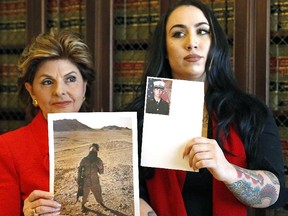 Former Marine Erika Butner (right) stands with attorney Gloria Allred holding photos of Butner in uniform as she and another active-duty female Marine said photographs of them were secretly posted online without their consent, at a news conference in Los Angeles, Wednesday, March 8, 2017. (AP Photo/Nick Ut)